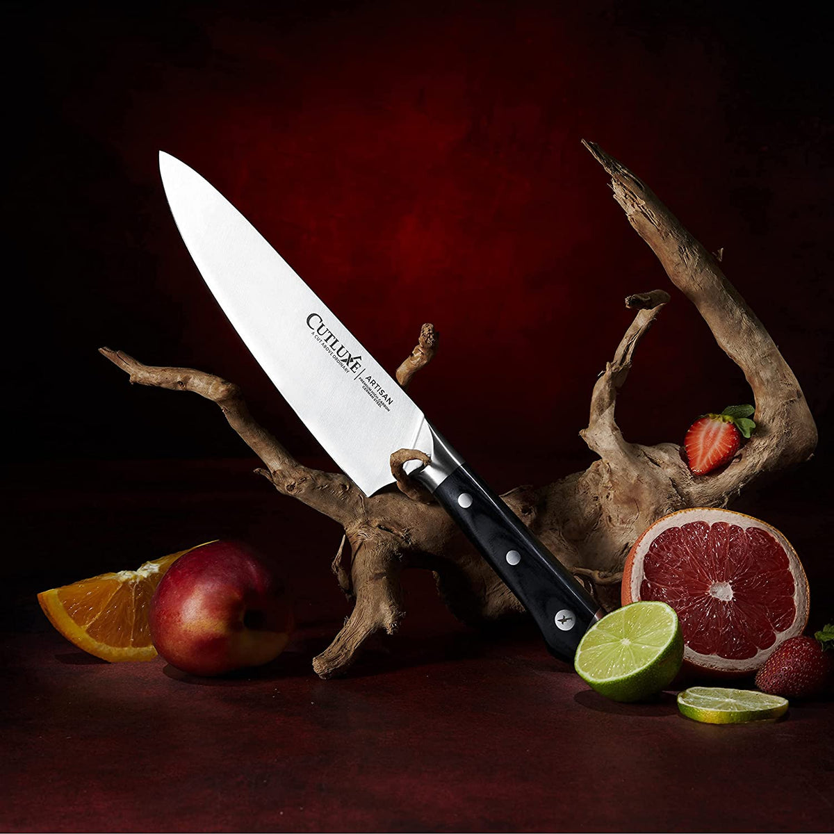 Product image 6 of 9: Cutluxe Artisan chef knife with black handle, displayed with fresh citrus and fruit on dark wood