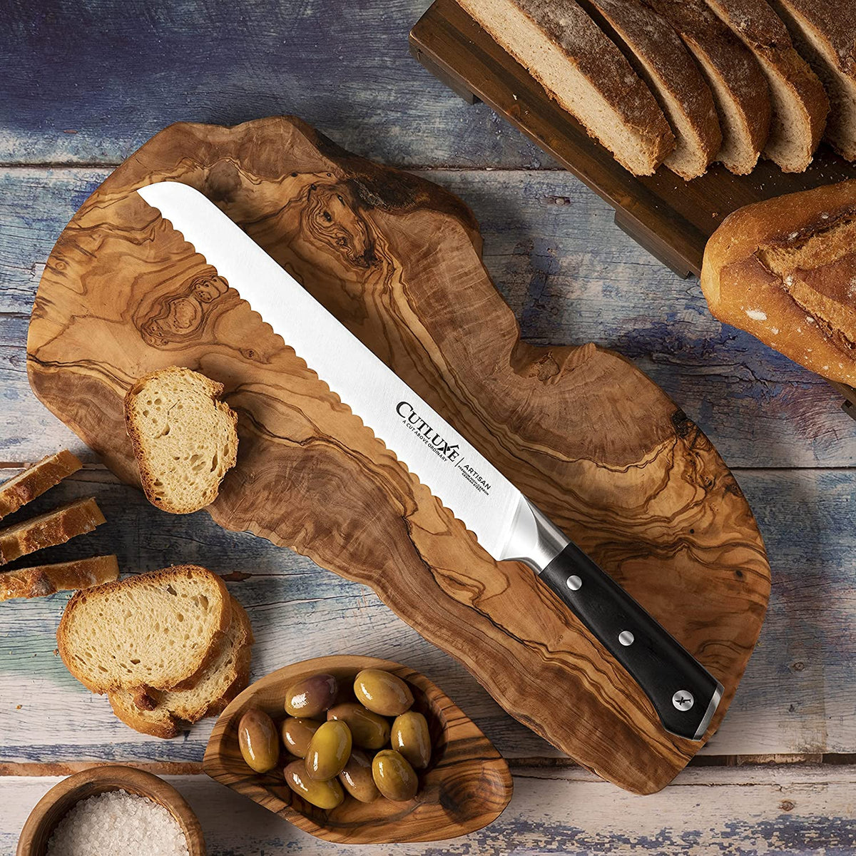 Product image 6 of 9: Serrated bread knife on wooden board with sliced bread and olives, ideal for home cooks and chefs