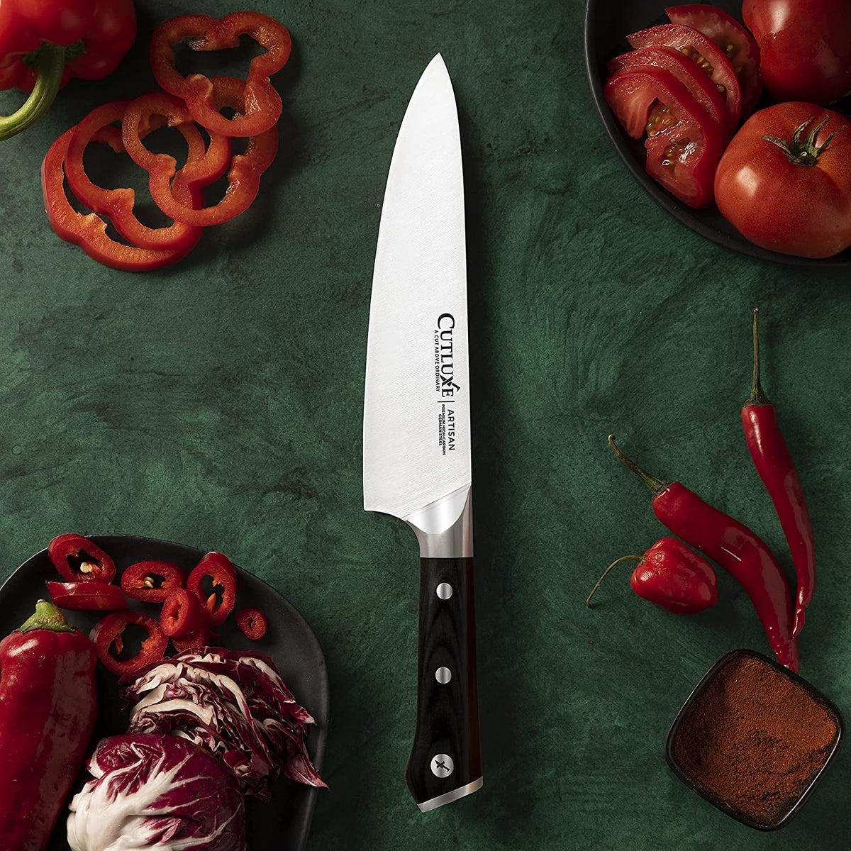 Product image 4 of 9: Professional chef knife with black handle, surrounded by sliced red peppers, tomatoes, and chili on green surface