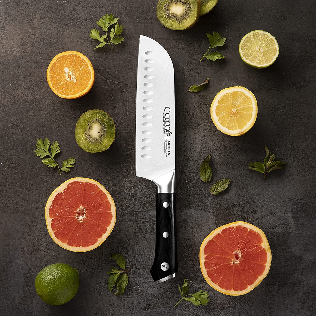 Product image 5 of 8: Cutluxe Artisan chef knife with black handle, surrounded by sliced citrus fruits and herbs on dark surface