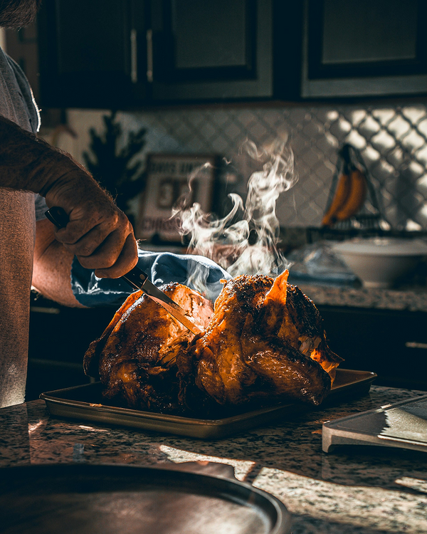 Slicing roasted turkey with sharp kitchen knife in home kitchen